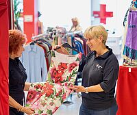 Verkäuferin zeigt Kundin ein Kleid